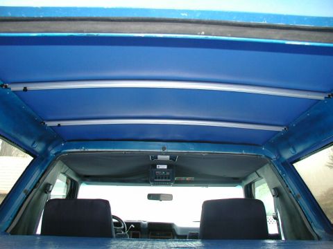 1985 Ford Bronco - The interior of a blue SUV features a custom headliner and a view of the dashboard and front seats.
