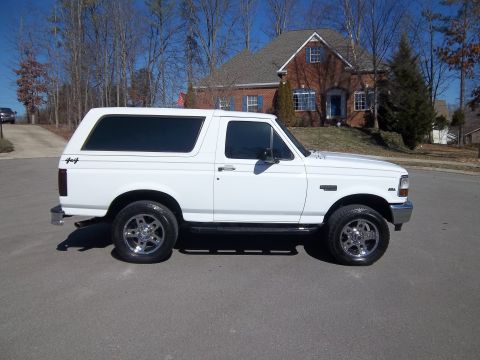 1995 Ford Bronco - Side view of a white 1995 Ford Bronco parked on a residential street.
