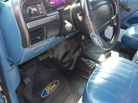 1995 Ford Bronco - The interior of a Ford truck features blue vinyl seats and a manual transmission shifter.