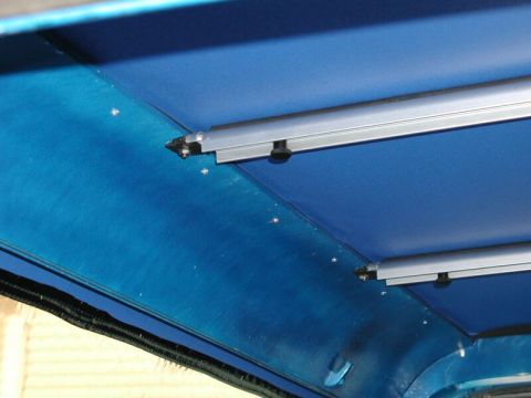 1985 Ford Bronco - Close-up of the blue soft top interior of a vehicle, showing mounting hardware.