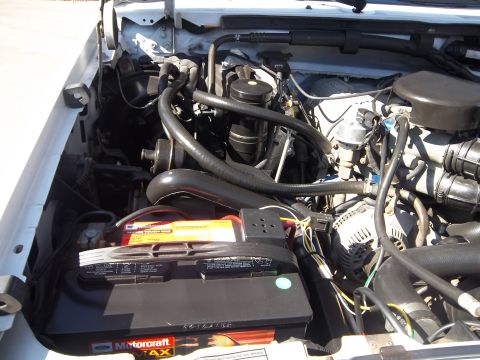 1995 Ford Bronco - The engine bay of a 1995 Ford Bronco is visible, the battery and various engine parts.