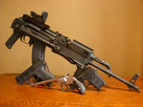1978 Ford Mustang II - Three firearms, including an AK-style rifle and two handguns, are displayed on a wooden table.