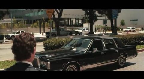 2000 Mercury Grand Marquis - A black sedan is seen driving on a street with other vehicles in the background.