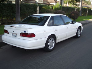 1993 Ford Taurus - This 1993 Ford Taurus sedan is viewed from the rear 3/4 angle, parked on a residential street.