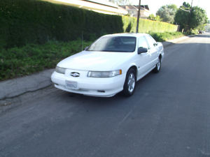 1993 Ford Taurus - A white 1993 Ford Taurus is parked on the side of a residential street.