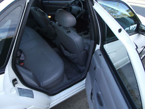 1993 Ford Taurus - The interior of a white sedan is visible through the open front and rear doors, showing the back seat and dashboard.
