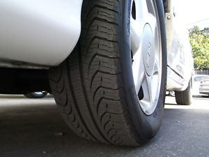 1993 Ford Taurus - A close-up view of a car's tire and wheel assembly, with another vehicle partially visible in the distance.
