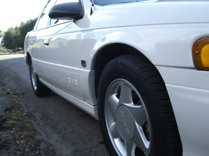 1993 Ford Taurus - Side view of a white 1993 Ford Taurus, highlighting its distinctive body style and alloy wheels.