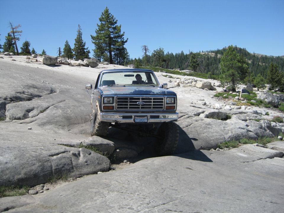 Blue 1980s pickup truck navigating rocky terrain