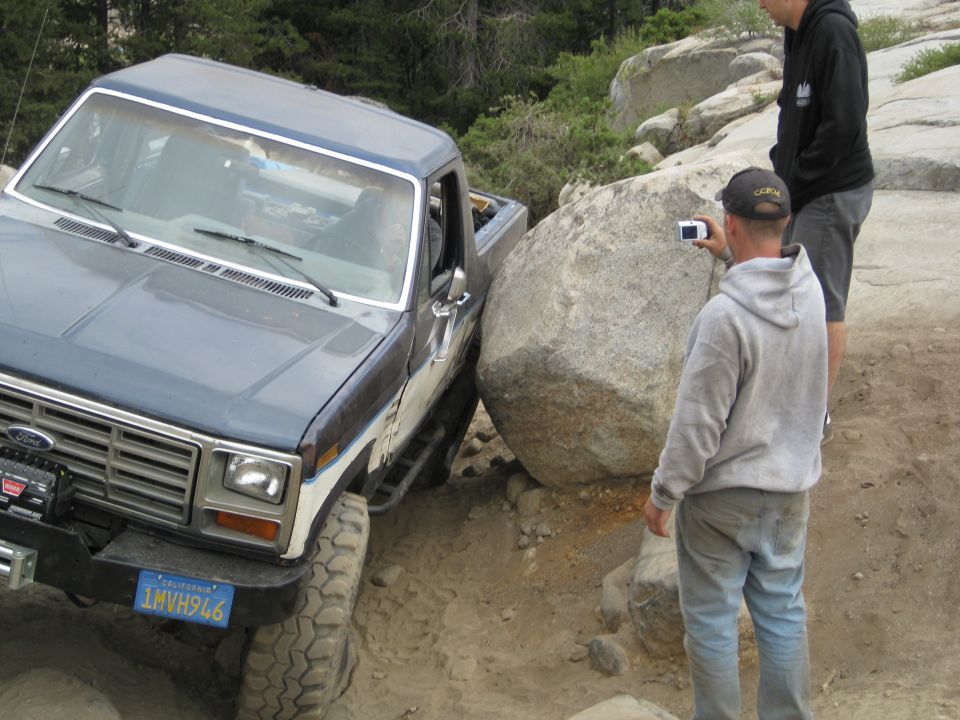 Blue and white 1986 Ford Bronco navigating a large boulder