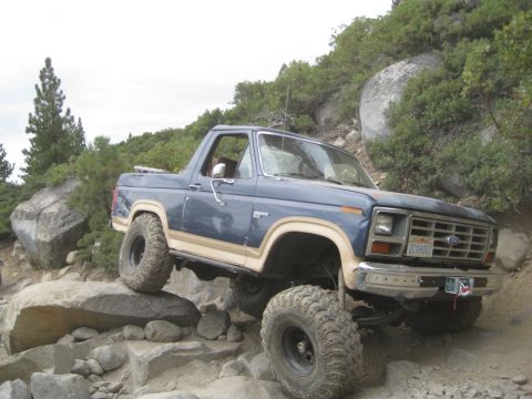 1986 Ford Bronco - This 1986 Ford Bronco is shown off-roading over large rocks on a steep incline.