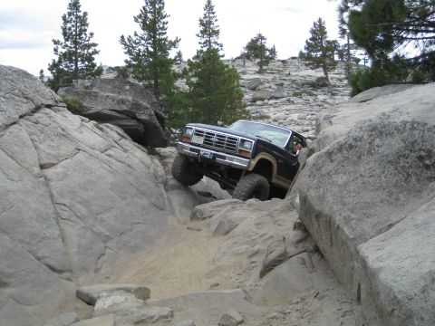 1986 Ford Bronco - Ford Bronco tackling a challenging off-road course with steep rock inclines.