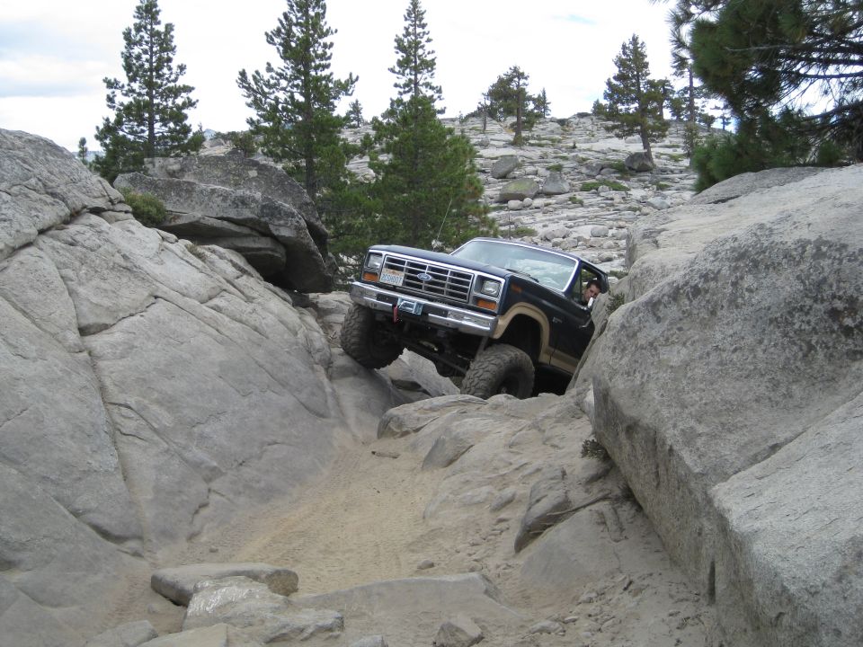 Ford Bronco navigating a narrow, rocky trail with large boulders
