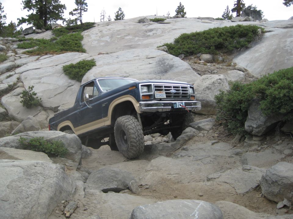 Blue and tan 1986 Ford Bronco navigating rocky terrain