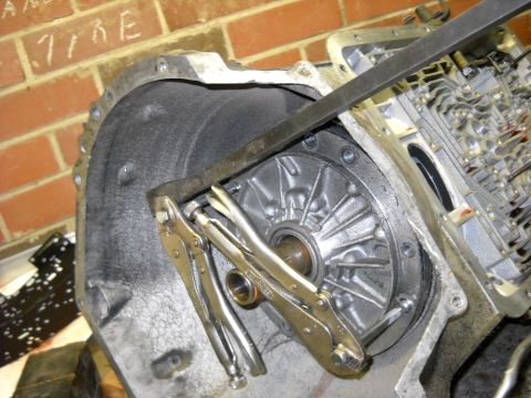 1993 Ford C-150 (Centurion Conversions) - A transmission torque converter is secured with locking pliers and a metal bar, likely during a rebuild process.