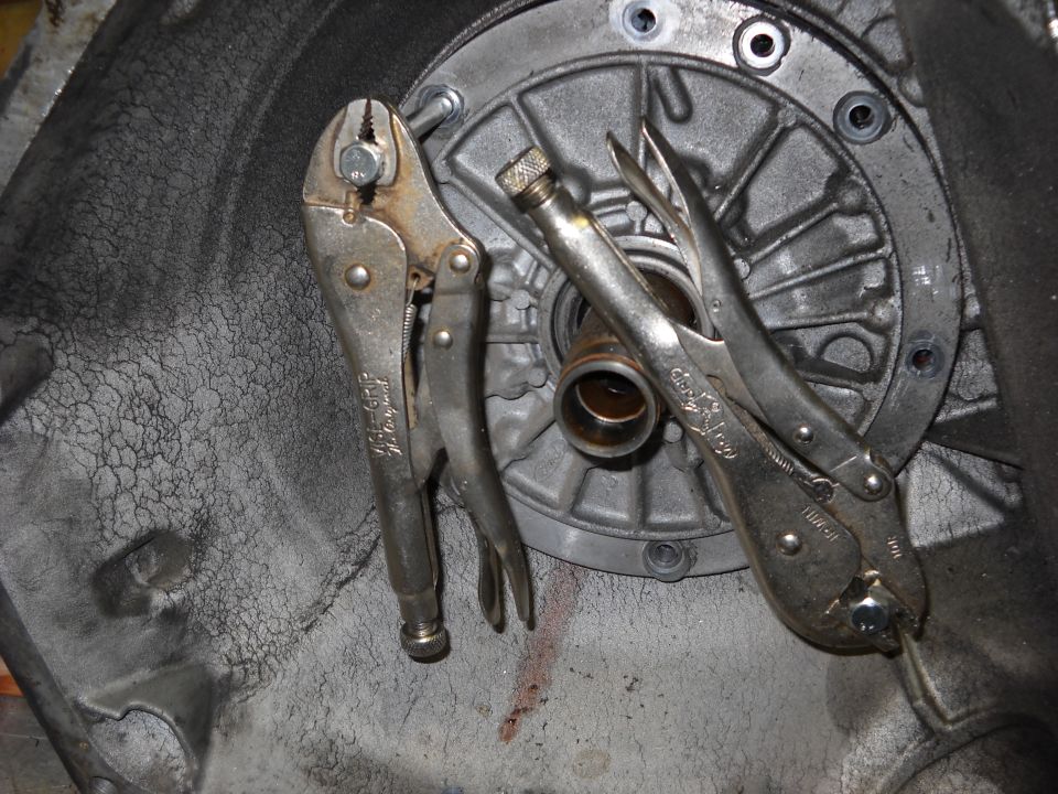 Two locking pliers gripping the front pump inside a transmission bellhousing