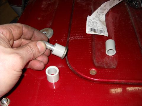 1993 Ford C-150 (Centurion Conversions) - A hand holds a bolt with a white sleeve and washer, with other parts and a label visible on a red surface.