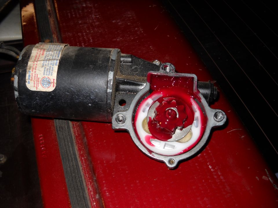 Windshield wiper motor with red grease inside the gear housing