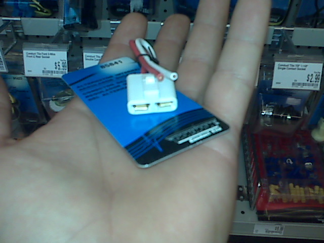 hand holding a white electrical connector on a blue card with red and white wires