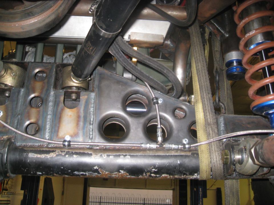 Close-up of custom suspension parts, including a shock absorber, metal brackets, and brake lines