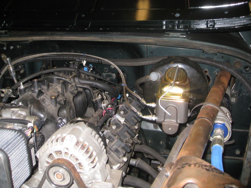 Engine bay showing a V8 engine, alternator, brake booster, and exhaust manifold