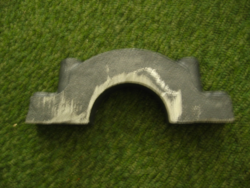 Gray metal automotive part with a semicircular cutout, showing tool marks