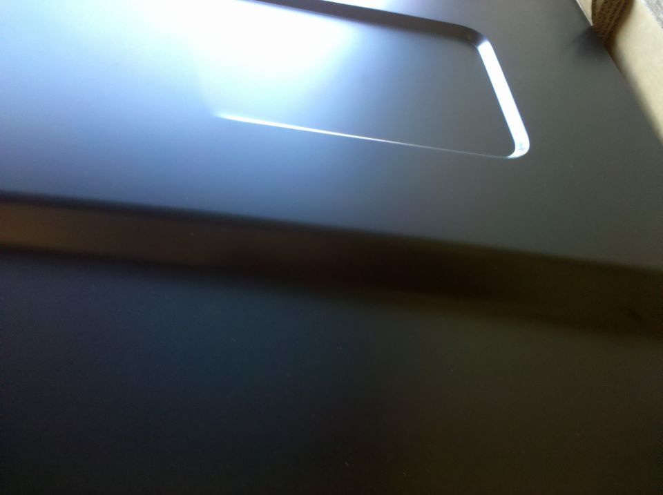 Close-up of a dark-colored vehicle hood with a rectangular indentation
