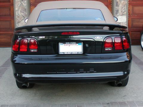 1992 Mercury Grand Marquis - The rear of a black Ford Mustang SVT Cobra convertible is shown, its distinctive taillights and 'COBRA' badging.