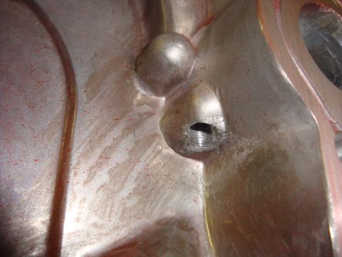 1989 Ford Bronco - Detail of a machined metal component, likely an engine part, showing casting marks and a threaded port.
