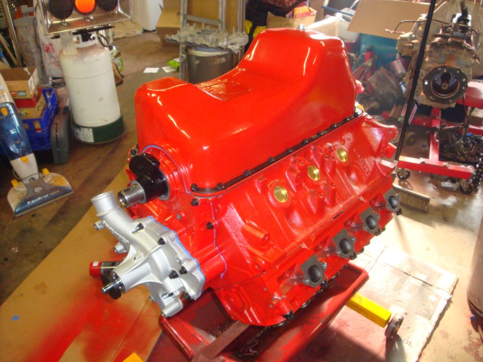 Gloss red rebuilt V8 short block on stand with bare aluminum water pump in garage