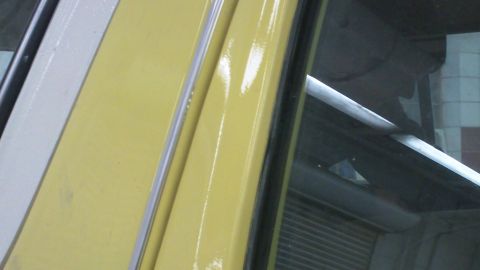 1978 Ford Bronco - A close-up view of the door frame and window trim of a yellow vehicle.