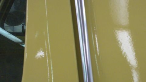 1978 Ford Bronco - Close-up of a yellow car door's chrome trim and painted surface.