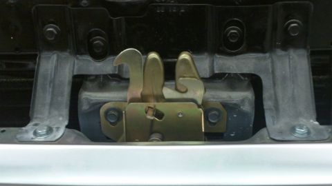 1978 Ford Bronco - Close-up of a vehicle's hood latch assembly, showing metal components and fasteners.