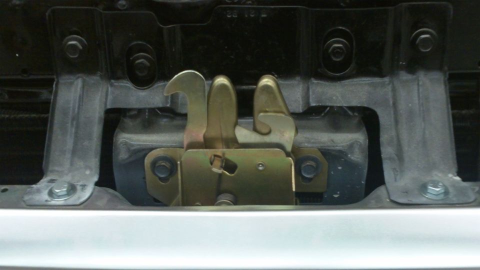 Hood latch mechanism with metal brackets and bolts