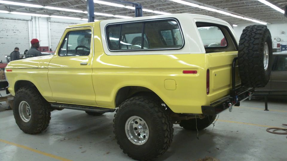 Yellow 1978 Ford Bronco with a white hardtop and a spare tire mounted on the rear bumper