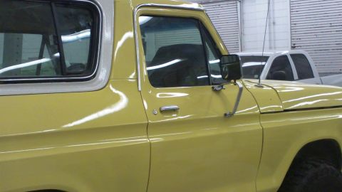 1978 Ford Bronco - Side view of a yellow 1978 Ford Bronco, with another vehicle in the background.