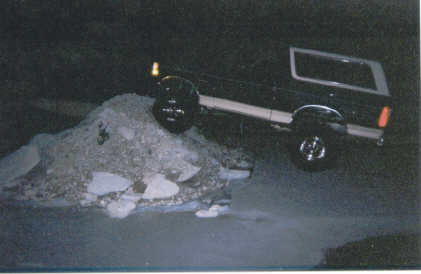 1967 Ford Mustang - A black Ford Bronco is captured mid-air as it drives over a pile of debris in the dark.