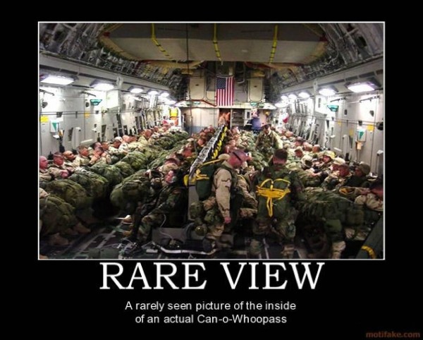 Soldiers in uniform packed inside a cargo plane, many with parachutes