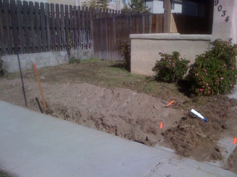1968 Ford Mustang - A trench has been dug in the yard, with orange markers indicating utility lines.