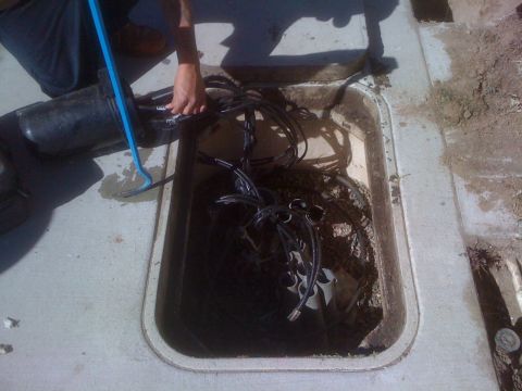 1968 Ford Mustang - A person works on untangling cables within an open underground utility access point.