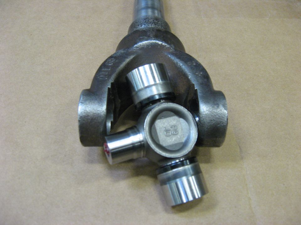 Driveshaft yoke with newly installed U-joint and shiny bearing caps on cardboard