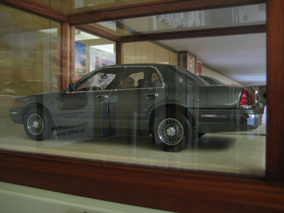 Dark gray 1998 Ford Crown Victoria model car, side view, in display case