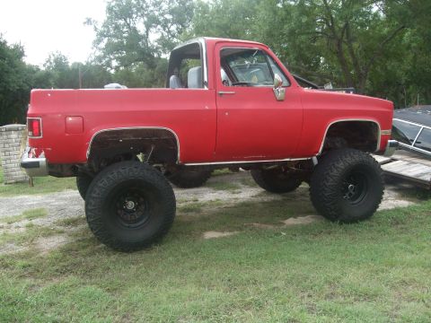 1979 Ford Bronco - This lifted red pickup truck is shown from the side. It appears to be a 1973 model.