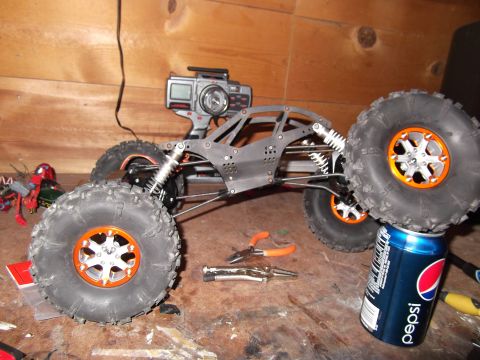 1989 Ford Bronco - RC rock crawler parts and tools are laid out on a workbench next to a Pepsi can.