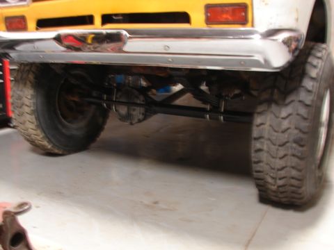 1971 International School Bus - The rear underside of a yellow school bus chassis is visible, showing its suspension and large tires.