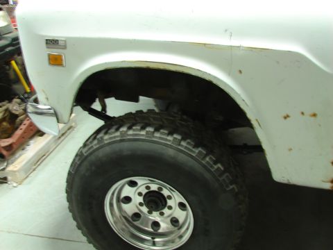 1971 International School Bus - Detail of a white International 100 pickup truck, showing the front wheel well and fender.