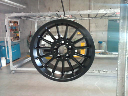 Black aftermarket wheel undergoing powder coating