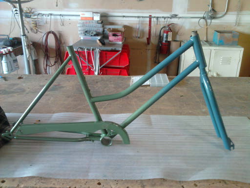 bicycle frame, painted green and blue, on a workbench
