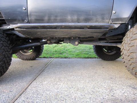 1996 Ford Bronco - This image shows the undercarriage of a black SUV, highlighting its rock sliders and off-road tires.