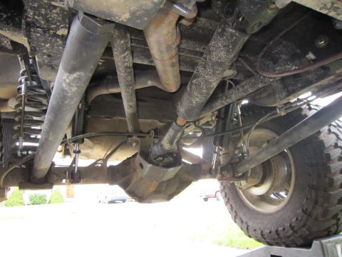 1996 Ford Bronco - The underside of a 4x4 vehicle reveals its robust drivetrain and suspension system, including the rear differential and driveshaft.